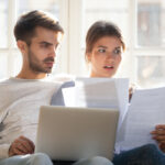Couple,Sitting,On,Couch,At,Home,Use,Pc,Reading,Letter