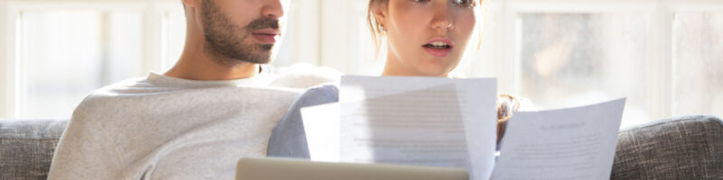 Couple,Sitting,On,Couch,At,Home,Use,Pc,Reading,Letter